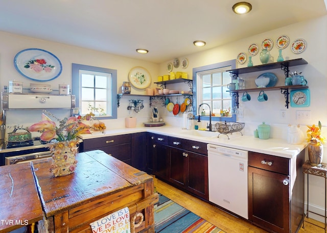 kitchen featuring plenty of natural light, white dishwasher, open shelves, and a sink