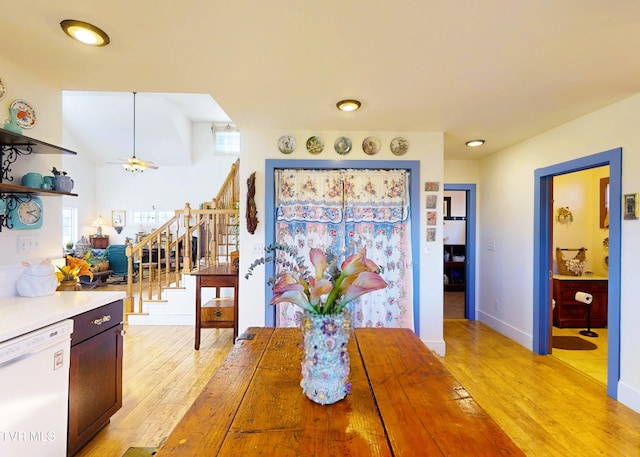 dining area featuring baseboards, ceiling fan, light wood finished floors, and stairs