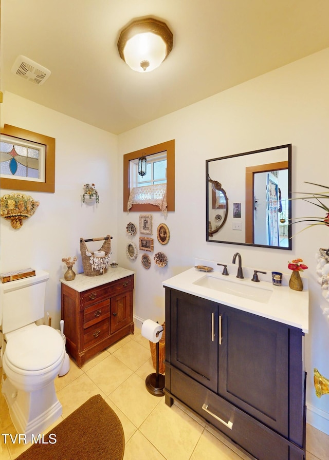 bathroom with visible vents, toilet, vanity, baseboards, and tile patterned floors