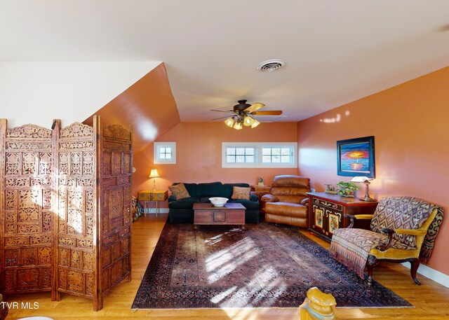 living area featuring ceiling fan, wood finished floors, visible vents, and baseboards