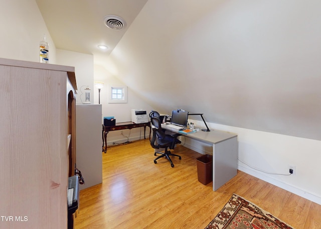 office with light wood finished floors, visible vents, and vaulted ceiling