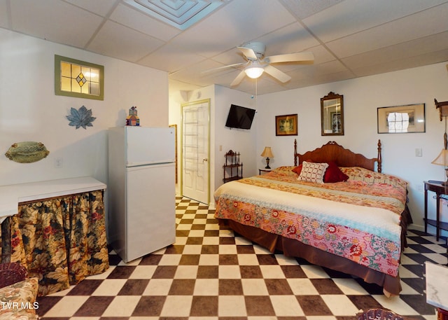 bedroom featuring ceiling fan, freestanding refrigerator, a paneled ceiling, and tile patterned floors