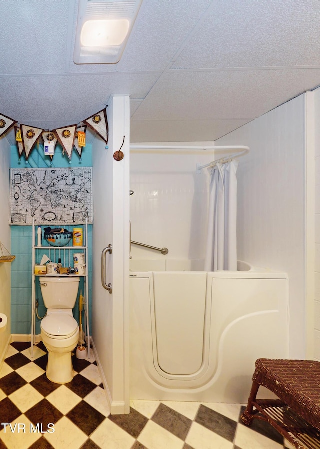 bathroom with a shower with curtain, a bathtub, toilet, and tile patterned floors