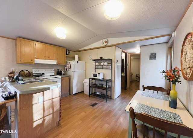 kitchen with white appliances, light wood-style flooring, vaulted ceiling, under cabinet range hood, and a sink