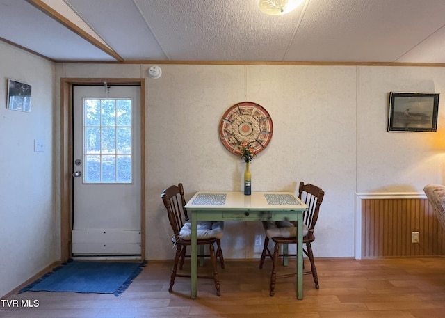 dining room featuring a textured ceiling, ornamental molding, and wood finished floors