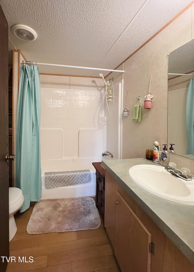 full bathroom featuring a textured ceiling, vanity, wood finished floors, and visible vents