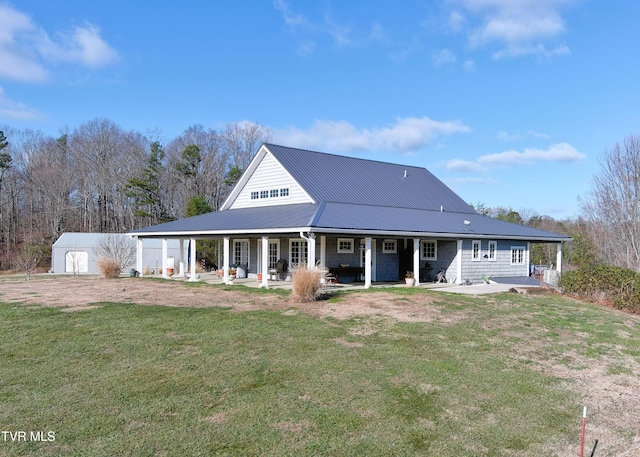 rear view of property featuring a porch, an outbuilding, metal roof, and a yard