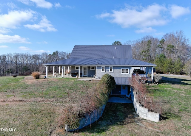 back of property featuring covered porch, metal roof, and a lawn