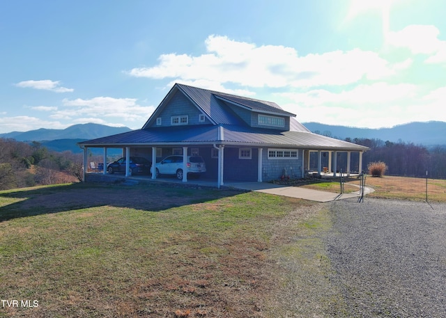 farmhouse with a front yard, metal roof, a mountain view, and driveway