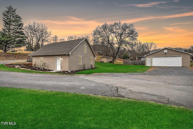 property exterior at dusk featuring a lawn, an outbuilding, and a garage