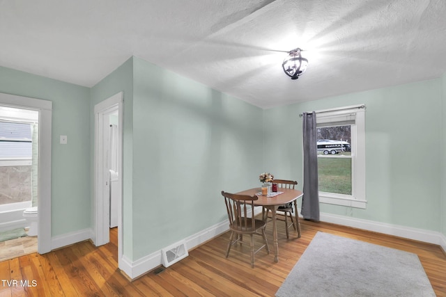 dining area with a healthy amount of sunlight, a textured ceiling, and hardwood / wood-style flooring