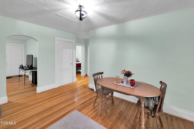 dining area with light wood-type flooring and a textured ceiling