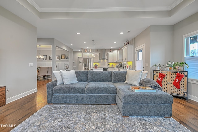 living room featuring sink, ornamental molding, dark wood-type flooring, and a chandelier