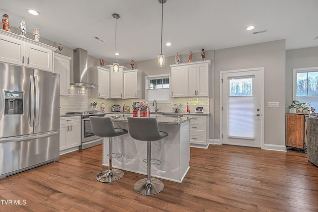 kitchen featuring stainless steel appliances, white cabinetry, and wall chimney exhaust hood