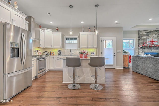 kitchen featuring white cabinets, a center island, stainless steel appliances, and hardwood / wood-style flooring