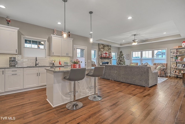 kitchen featuring a tray ceiling, white cabinetry, ceiling fan, and dark hardwood / wood-style floors