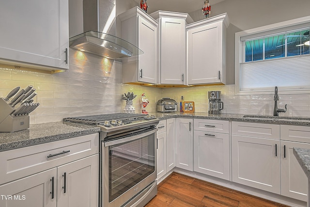 kitchen with white cabinets, sink, stainless steel stove, wall chimney exhaust hood, and dark hardwood / wood-style flooring