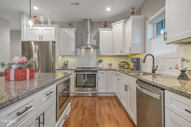 kitchen featuring white cabinets, wall chimney range hood, sink, dark hardwood / wood-style floors, and appliances with stainless steel finishes