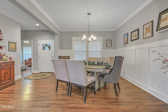 dining space with a notable chandelier, wood-type flooring, and ornamental molding