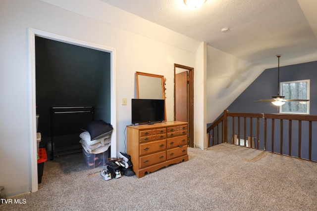 bedroom with a textured ceiling, carpet floors, and vaulted ceiling