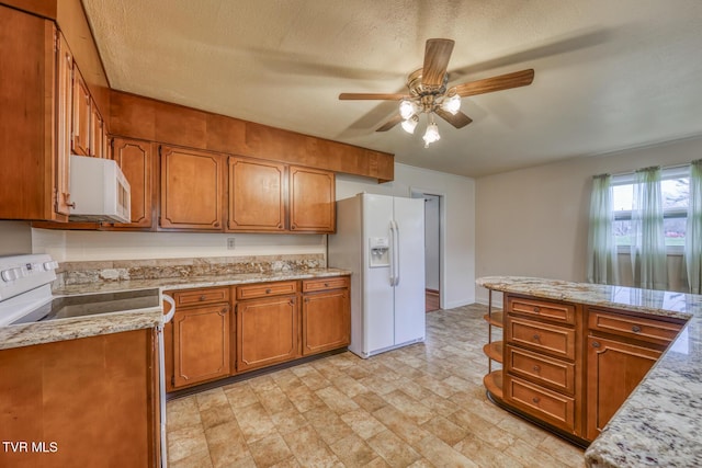 kitchen with ceiling fan, light stone countertops, white appliances, and a textured ceiling