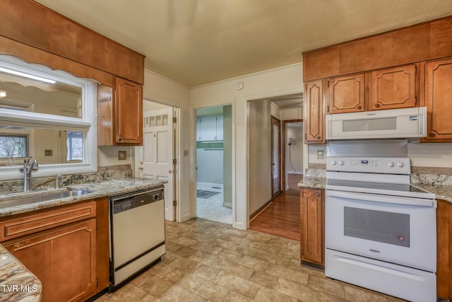 kitchen with white appliances, light stone counters, and sink