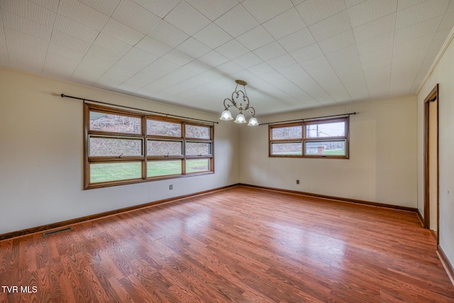 spare room with hardwood / wood-style flooring and a notable chandelier