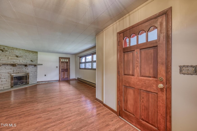 foyer entrance with hardwood / wood-style flooring, a fireplace, and a baseboard heating unit