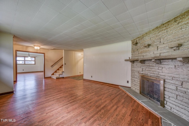 unfurnished living room featuring hardwood / wood-style floors and a stone fireplace