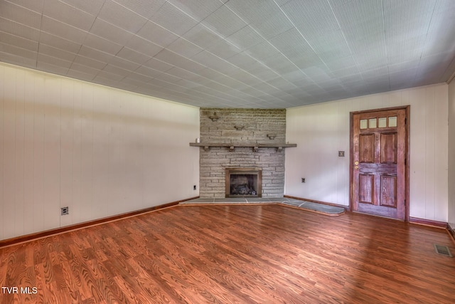 unfurnished living room featuring hardwood / wood-style floors and a stone fireplace