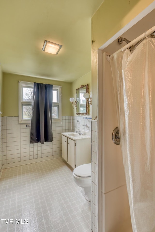 bathroom with vanity, toilet, tile walls, and curtained shower