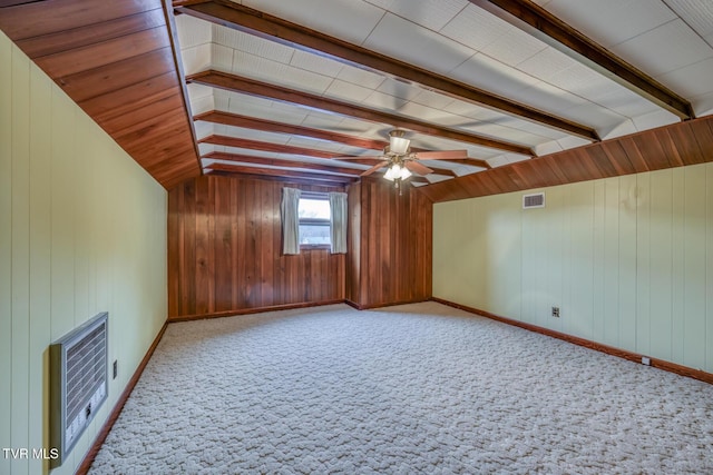 additional living space with heating unit, ceiling fan, wooden walls, lofted ceiling with beams, and carpet floors