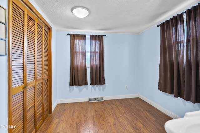 unfurnished bedroom with wood-type flooring, a textured ceiling, and a closet