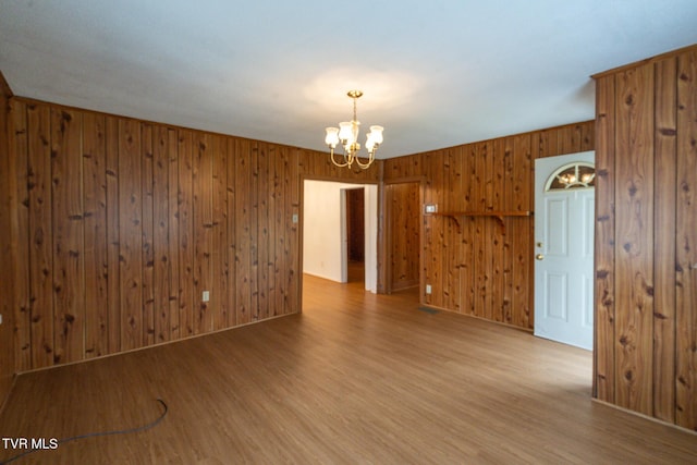 spare room with hardwood / wood-style floors and a notable chandelier