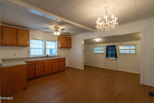 kitchen featuring pendant lighting, ceiling fan with notable chandelier, sink, ornamental molding, and wood-type flooring