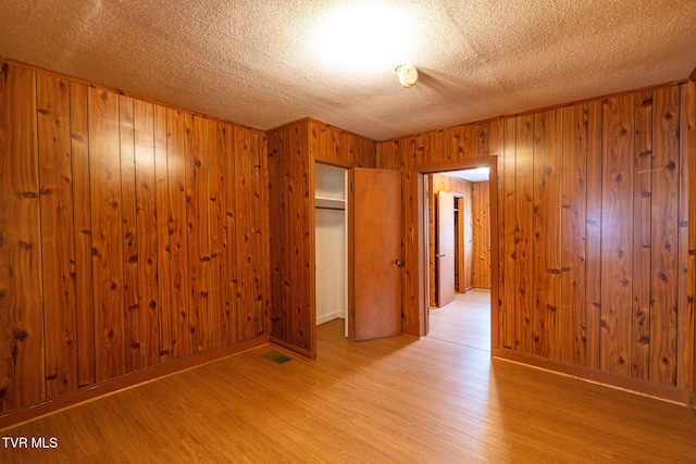 unfurnished room featuring a textured ceiling and light hardwood / wood-style flooring