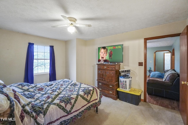 carpeted bedroom featuring ceiling fan and a textured ceiling