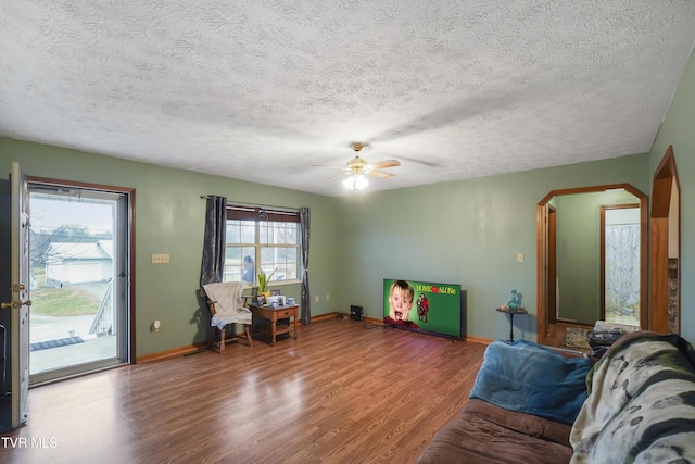 living room featuring ceiling fan, wood-type flooring, and a textured ceiling