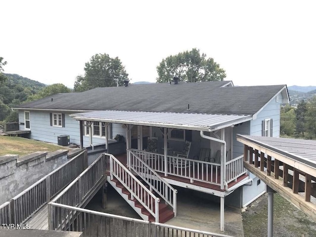 back of property featuring metal roof, central AC, and stairway