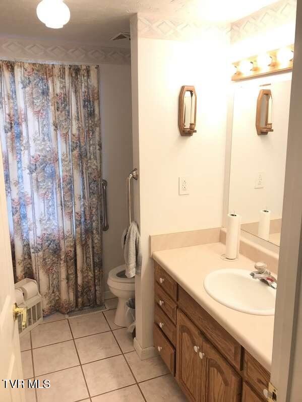 full bathroom with tile patterned flooring, vanity, and toilet