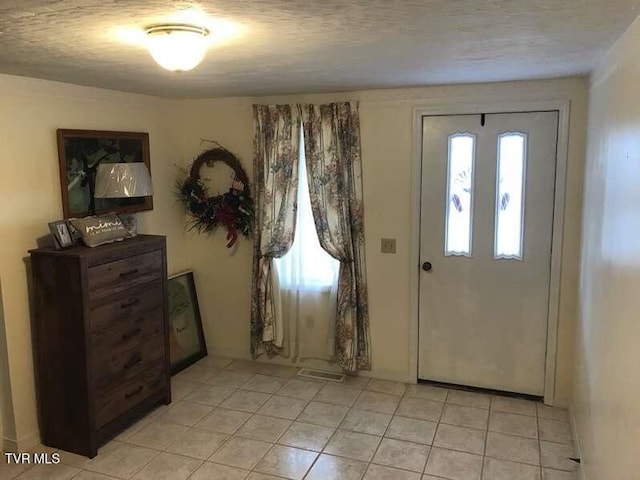 entrance foyer with light tile patterned flooring and a textured ceiling