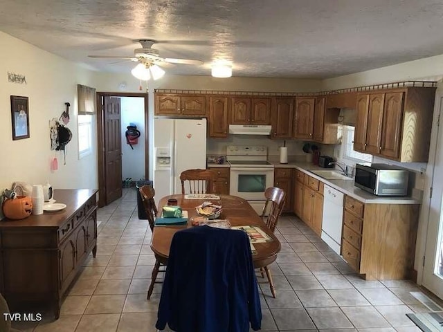 kitchen featuring brown cabinets, light countertops, a sink, white appliances, and under cabinet range hood