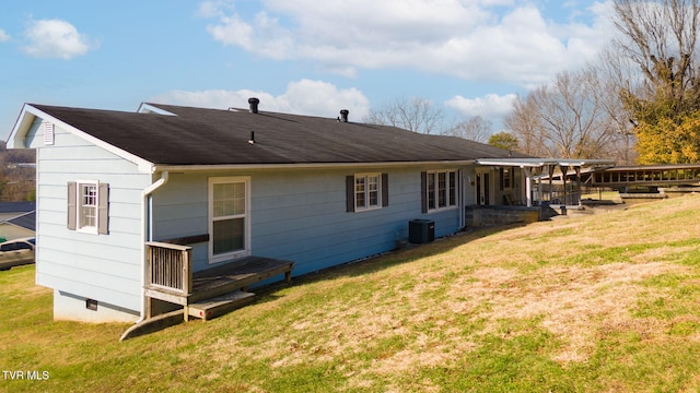 back of property with central AC, crawl space, and a lawn