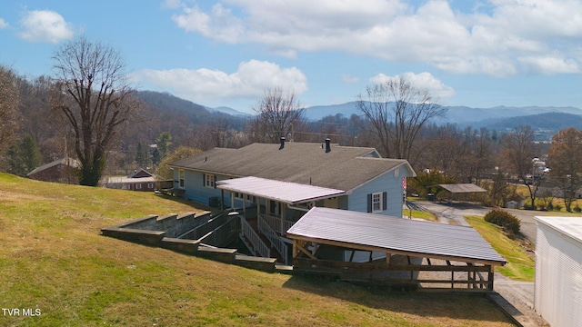 exterior space featuring a mountain view, metal roof, and a yard