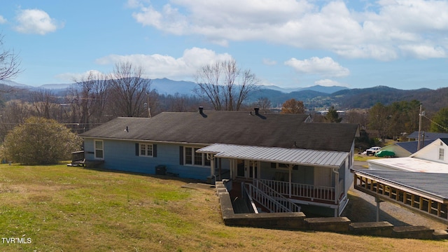 rear view of property with a sunroom, a mountain view, and a lawn