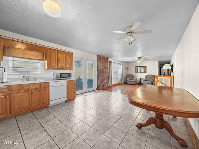 kitchen with dishwasher, stainless steel microwave, open floor plan, light countertops, and a sink