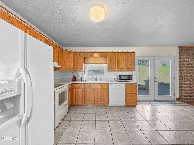 kitchen with white appliances, light countertops, under cabinet range hood, a sink, and light tile patterned flooring