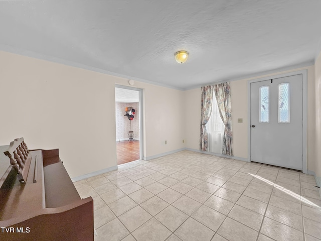 entrance foyer featuring a textured ceiling, baseboards, and light tile patterned floors