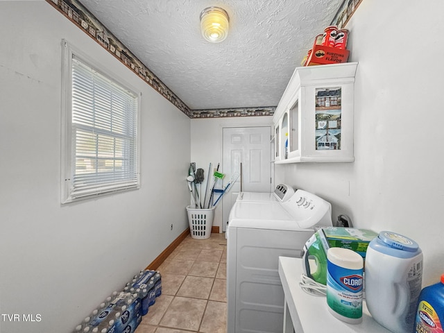 clothes washing area with laundry area, light tile patterned floors, baseboards, washing machine and clothes dryer, and a textured ceiling