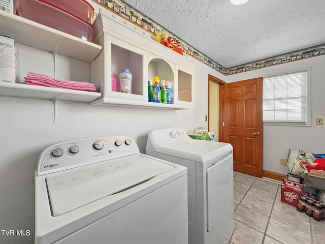 laundry area featuring a textured ceiling, laundry area, independent washer and dryer, and light tile patterned flooring